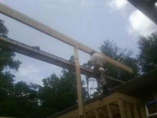 Carpenter setting a ridge beam over a new addition frame — Ice Dam Removal by Roofing Brothers in Swanzey