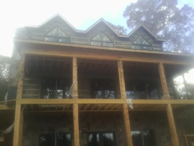 Dormers and porch framing on a large log home under construction — Roof Coating work by our crew in Swanzey