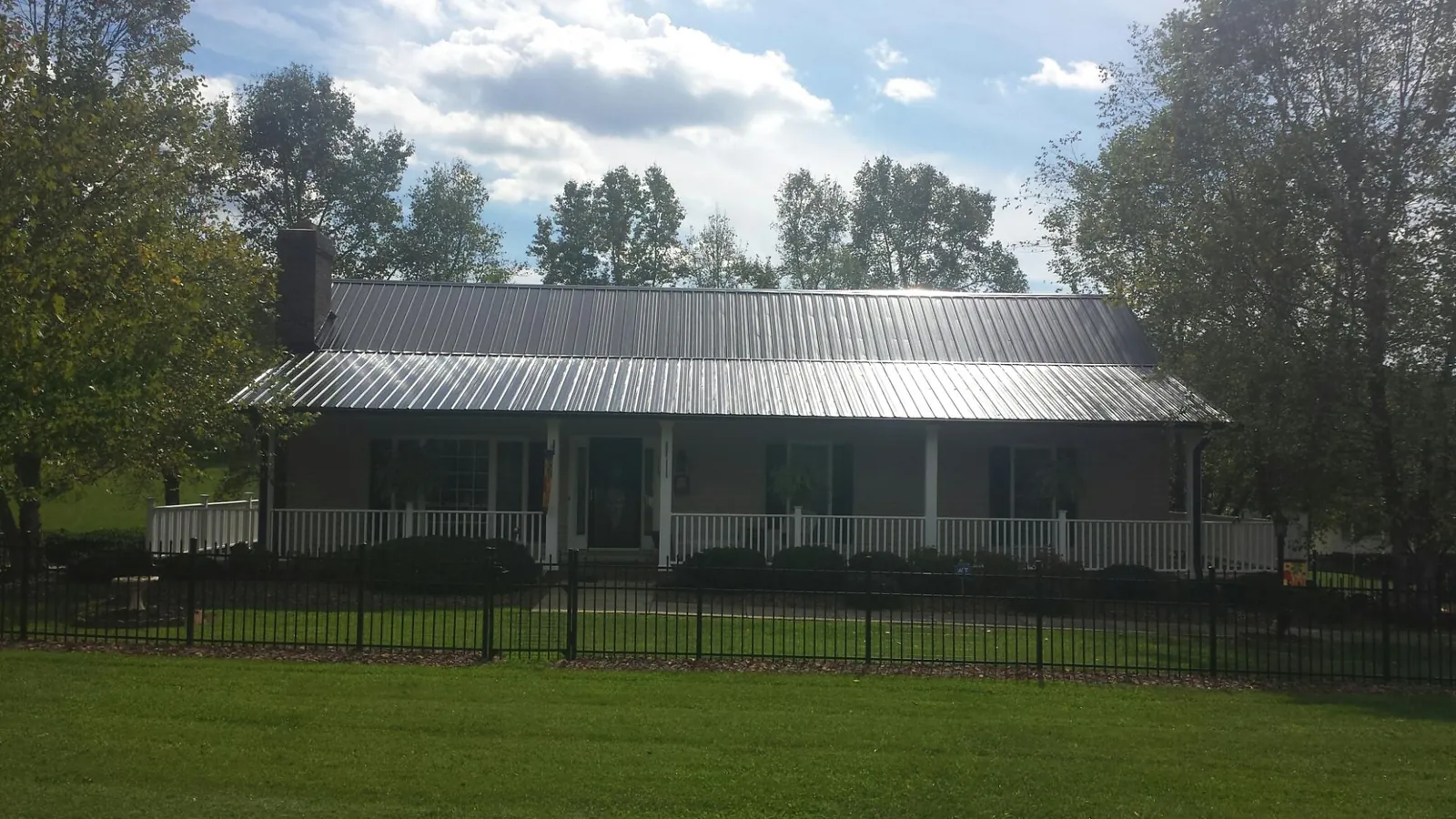 Gray metal roof on a brick ranch with a full width front porch — Gutter Guard Installation work by our crew in Swanzey