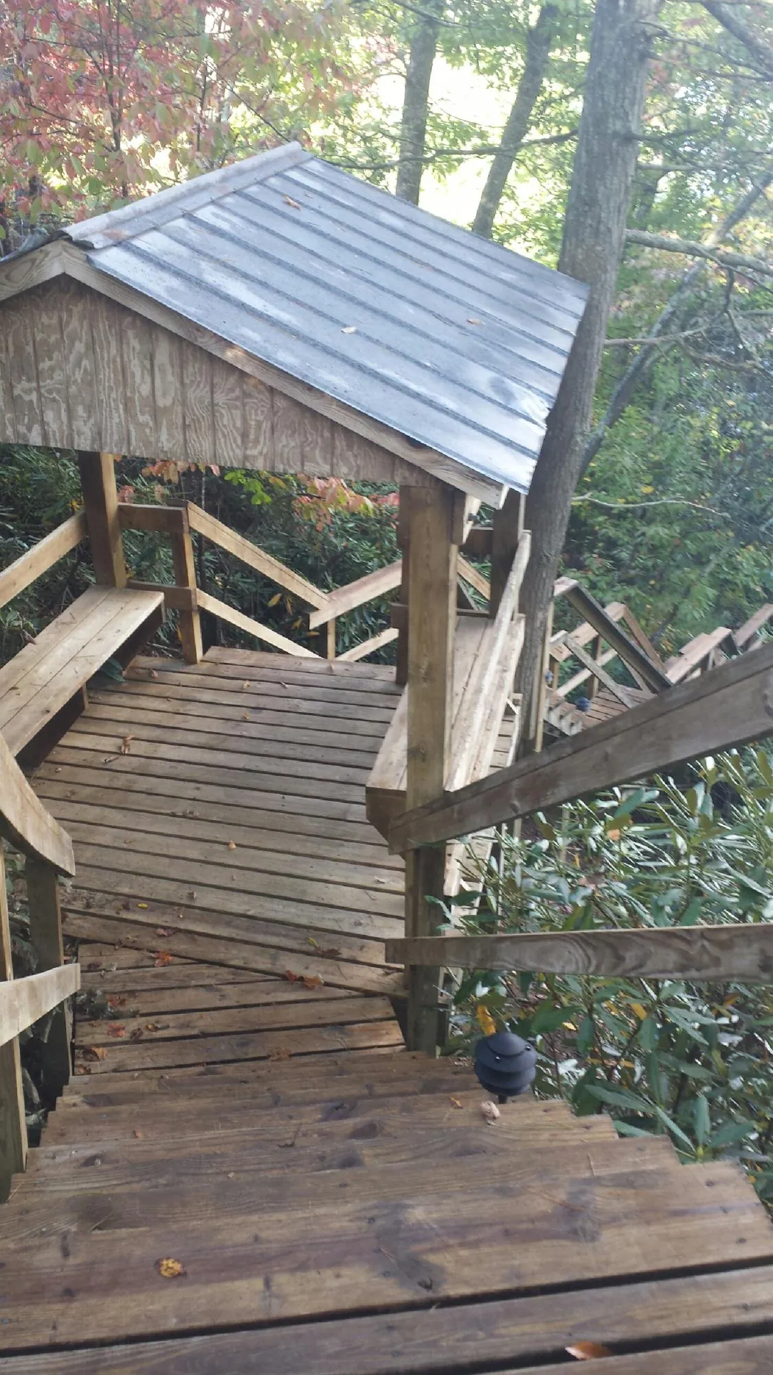Metal roofed shelter over wooden steps on a wooded walkway — Skylight Repair & Installation work by our crew in Swanzey