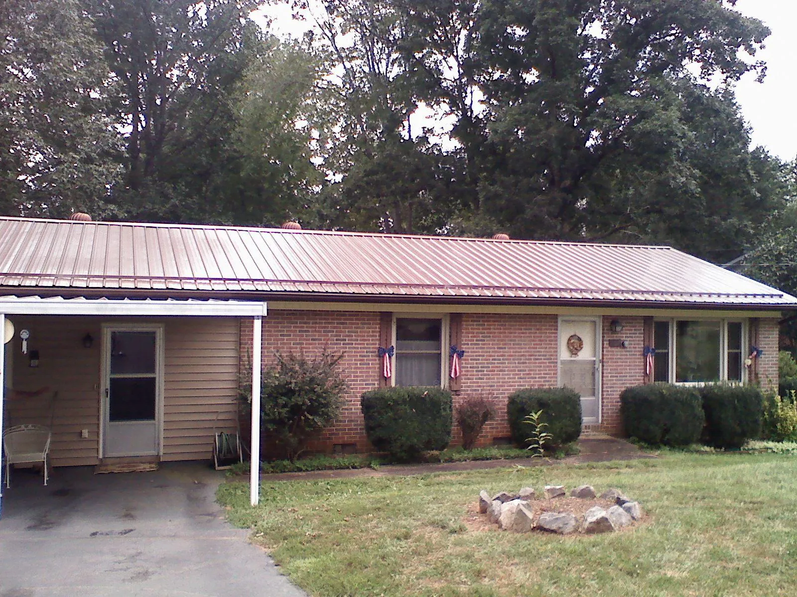 Bronze metal roof and carport on a brick ranch home — Roof Repair work by our crew in Swanzey