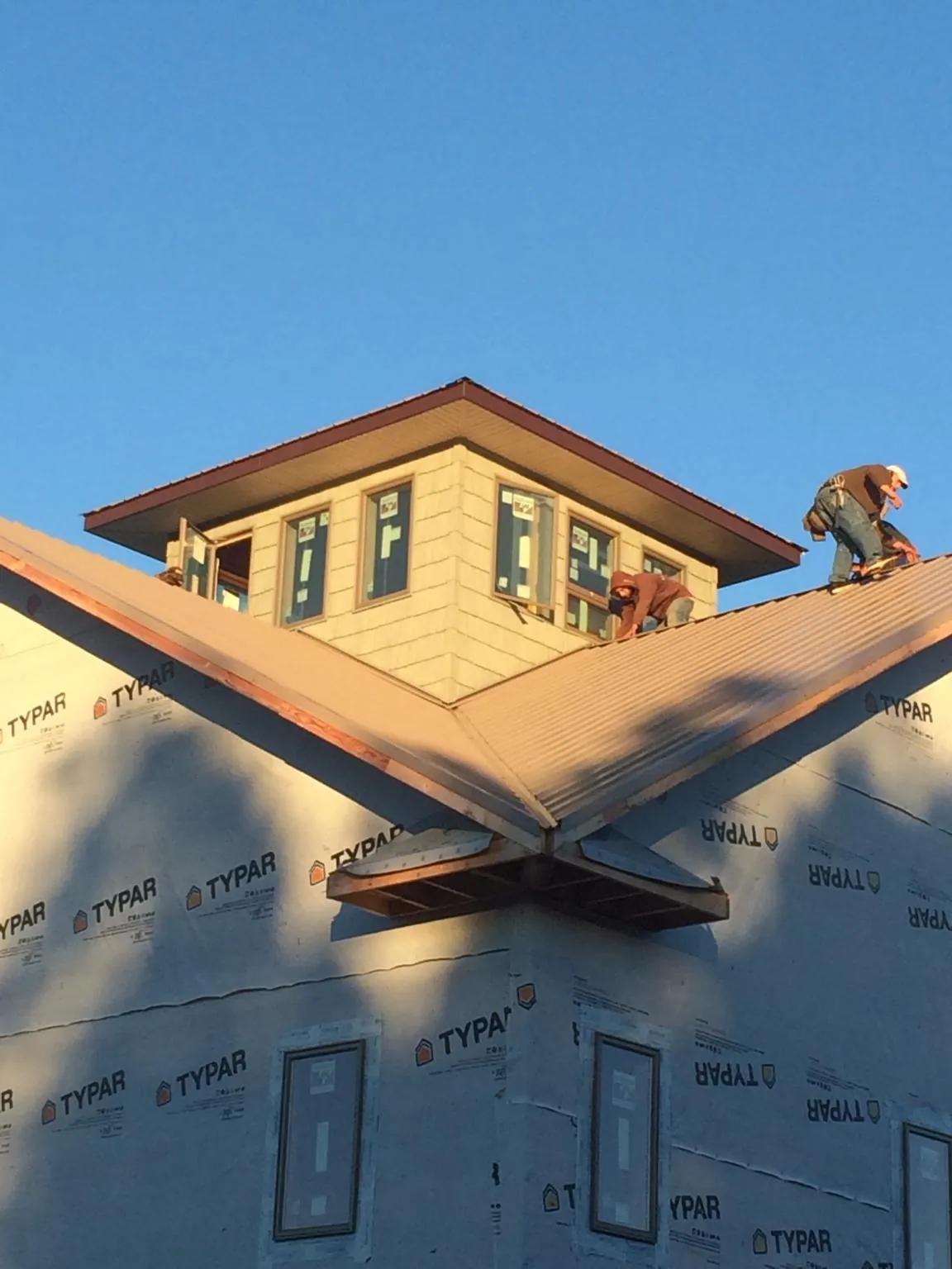 Roofers working around a rooftop cupola on a new metal roof at sunset — Roof Waterproofing in Swanzey by Roofing Brothers